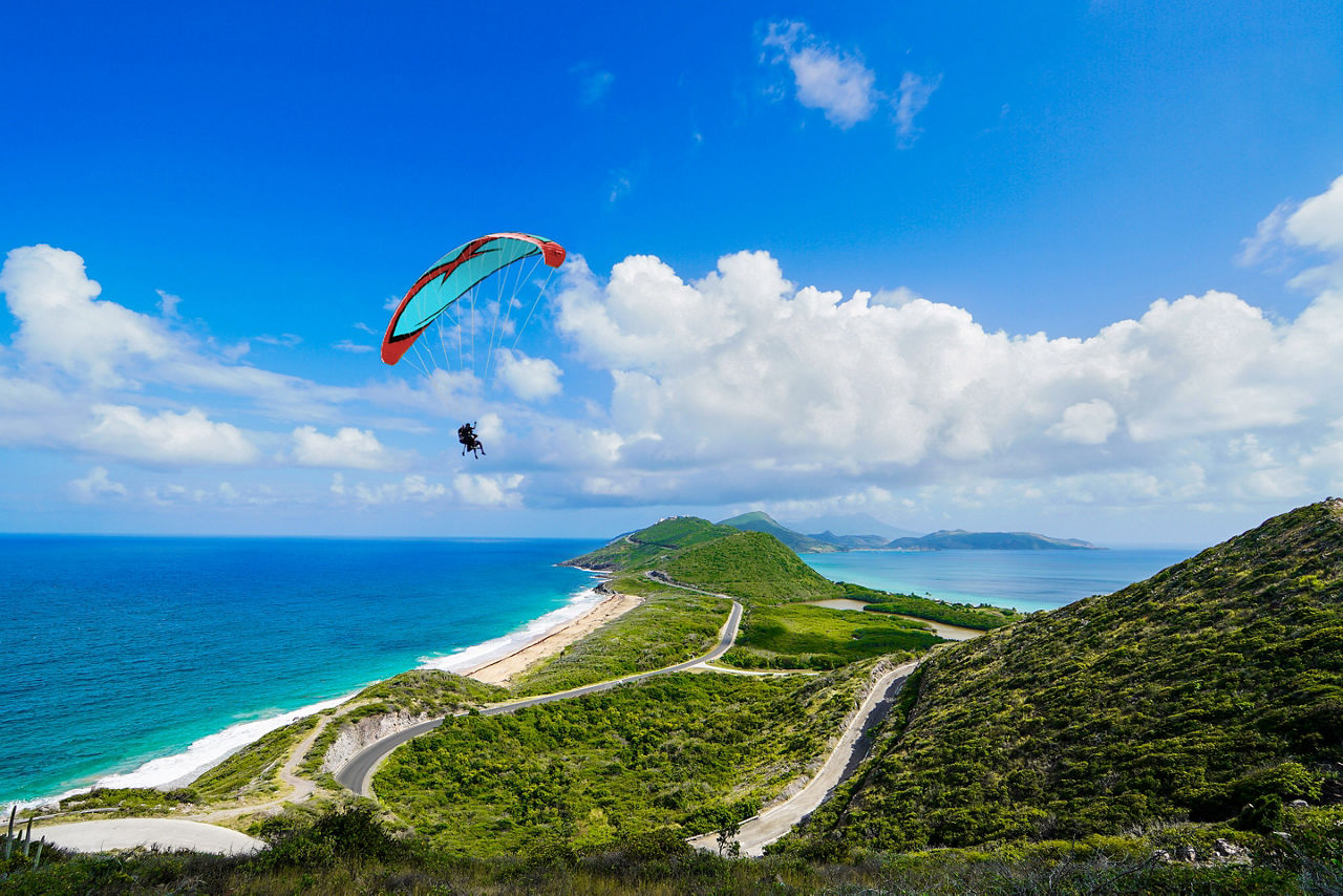 Man Paragliding by the Coast. Family Sitting by the Coast. Basseterre, St. Kitts Nevis 