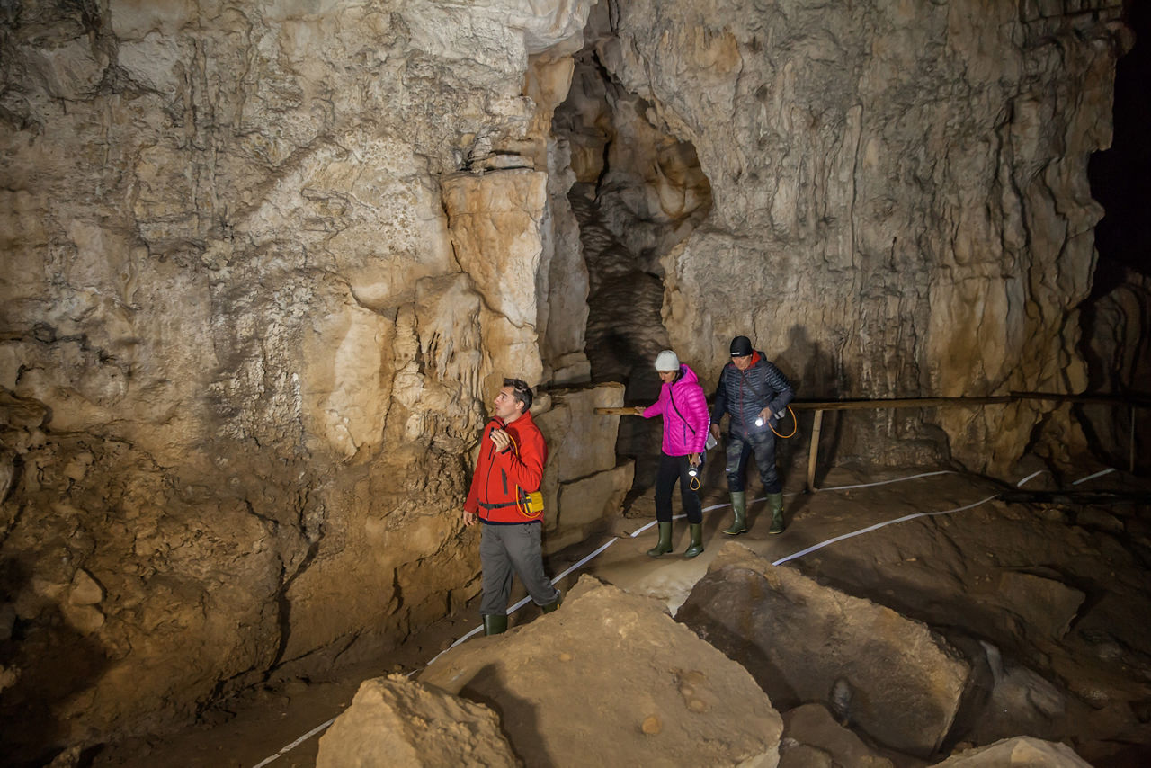 Shot of two tourists and a tourist guide walking in the cave
