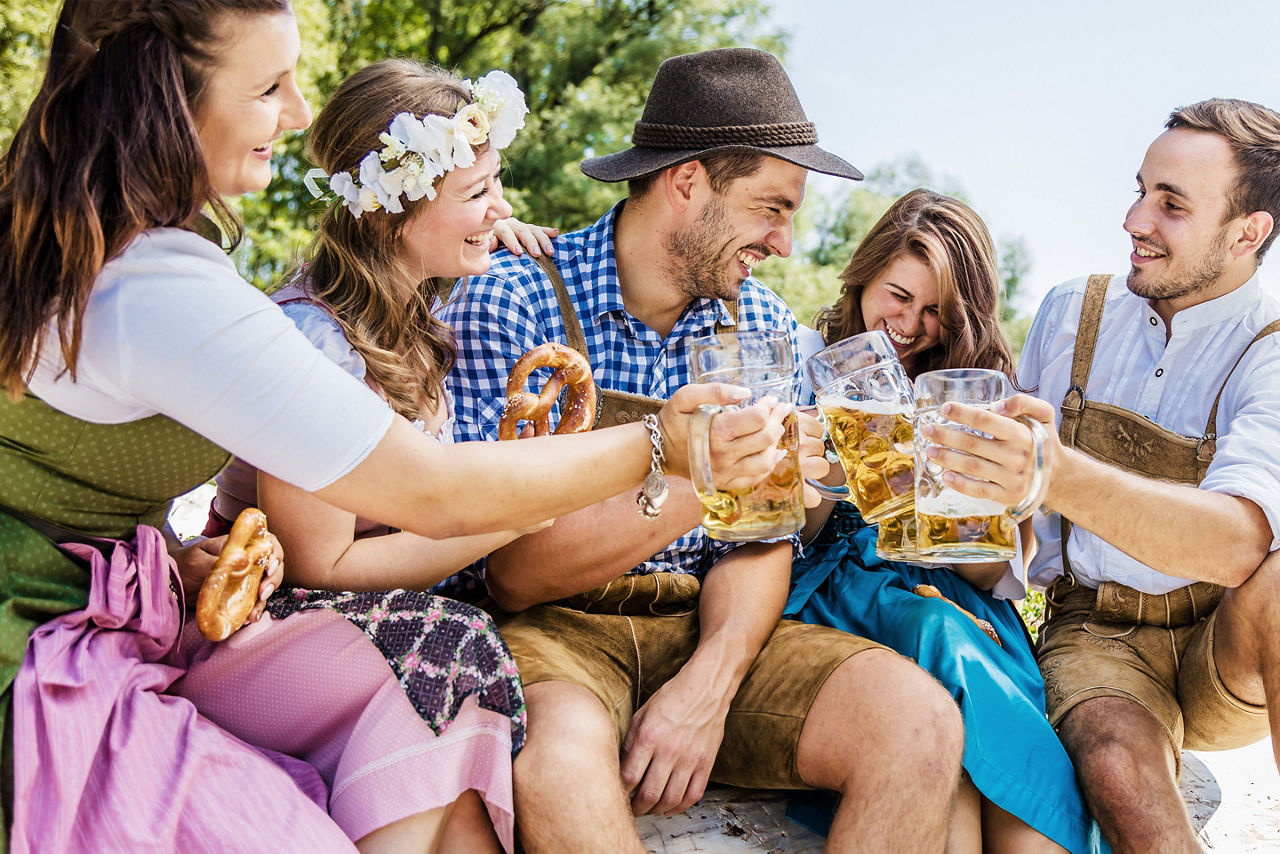 Five friends having fun on Bavarian RIver and clinking glasses with Oktoberfest