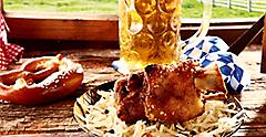 Roasted pork knuckle or hock with a crispy golden rind served with a pretzel and cold beer at a tavern offering traditional Bavarian cuisine to tourists