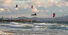 Kitesurfing in Tarifa. Plenty of colorful kites flying against a background of the mountains, beautiful clouds and waves of the Atlantic Ocean