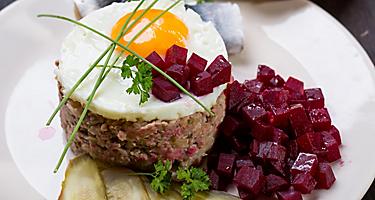 Traditional German labskaus seasoned meat, with a fried egg on top, and beetroots on the side, from a restaurant in Bremerhaven, Germany
