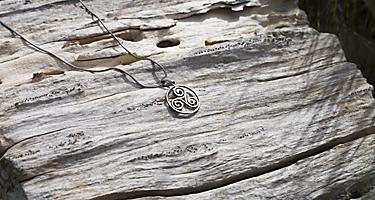 A silver necklace with a celtic symbol