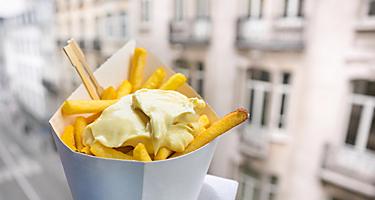 A container with fries topped with mayonnaise