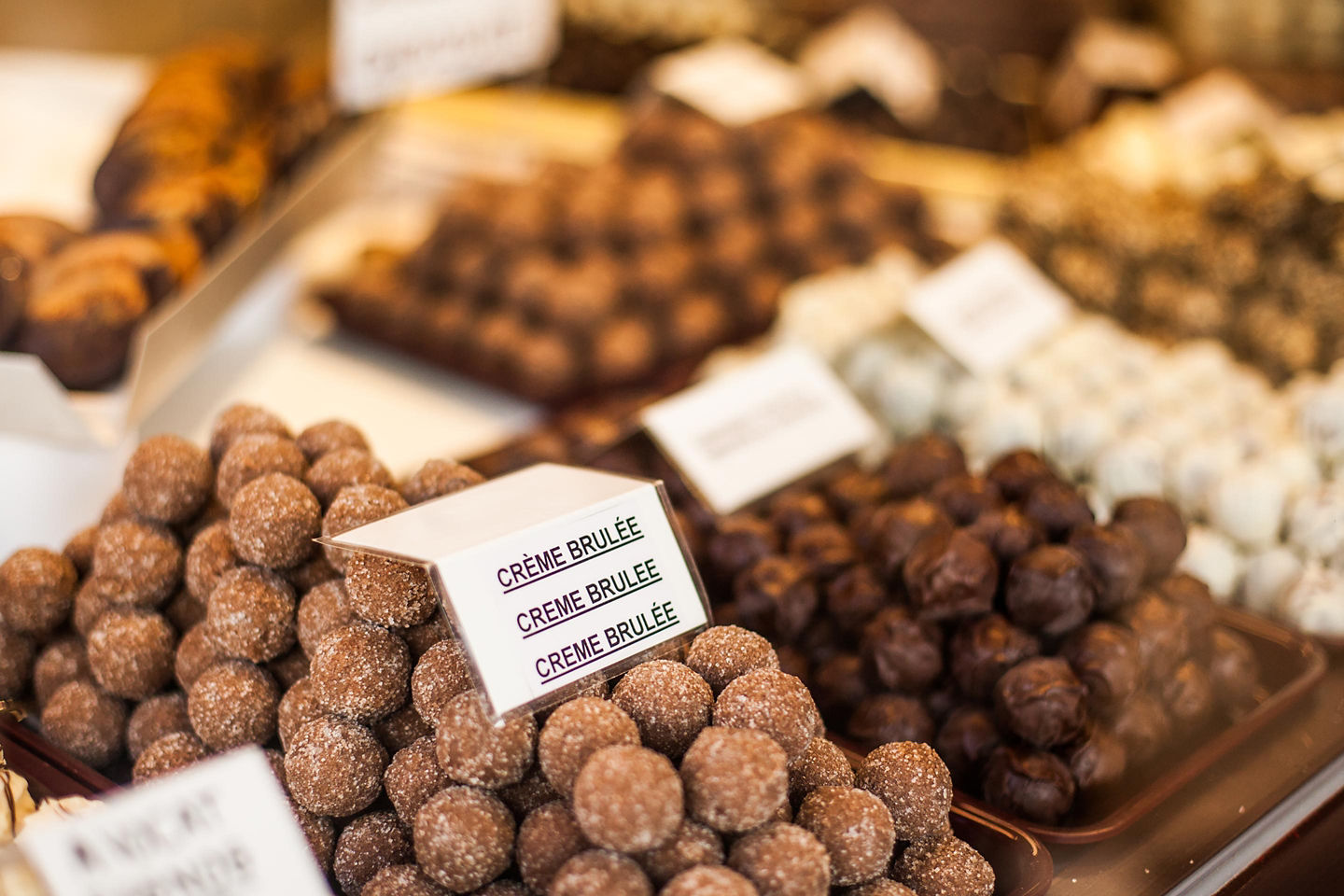 Assorted Belgian chocolates are arranged neatly, showcasing varied shapes, fillings, and glossy finishes. - Bruges, Belgium