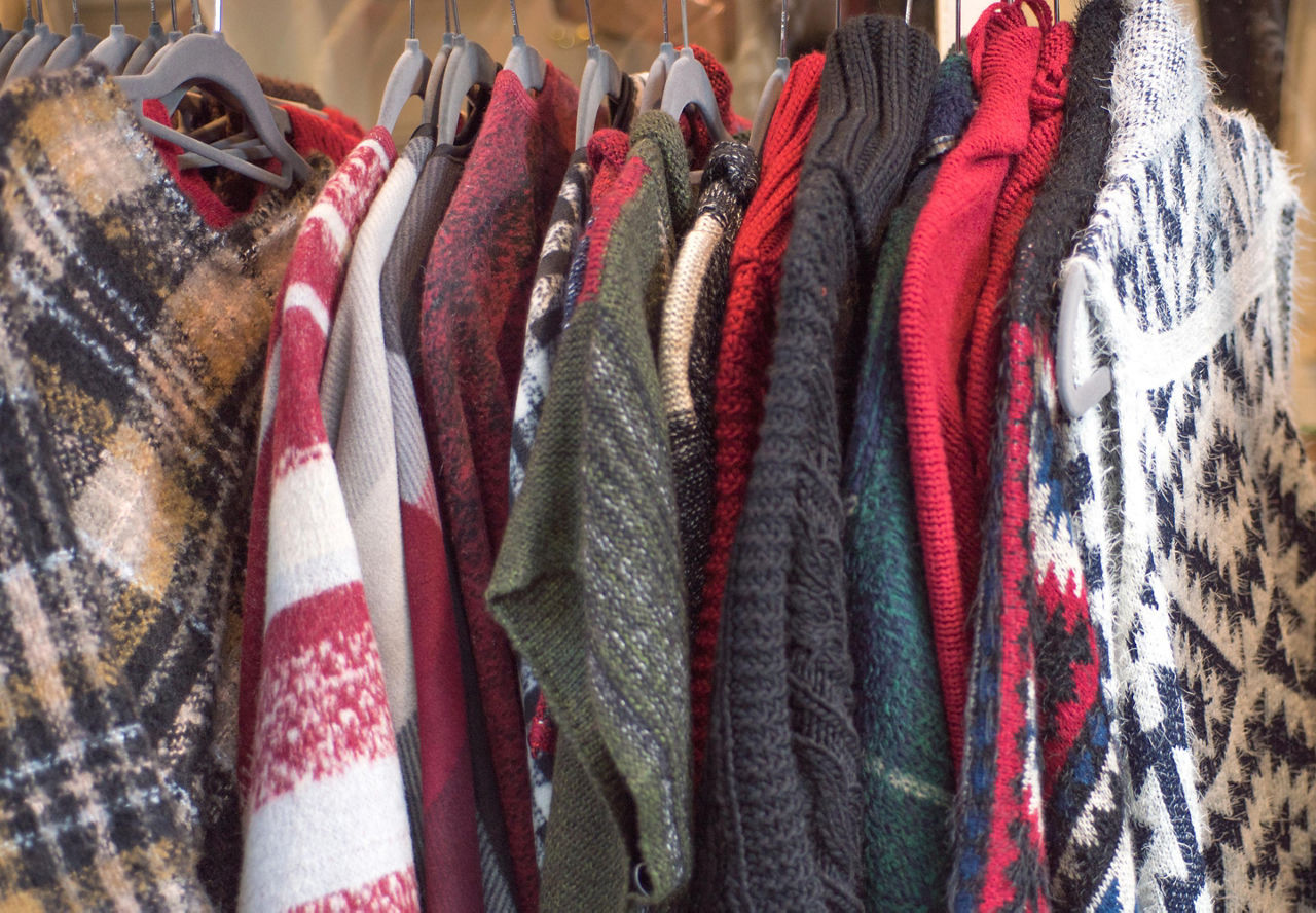 Various sweaters hanging on a rack at a shop