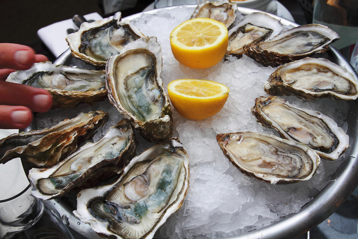 A dozen oysters on ice with a sliced lemon. - Cherbourg, France