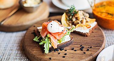 Danish smørrebrød sandwich with salmon fish and egg on wooden board, in Copenhagen, Denmark