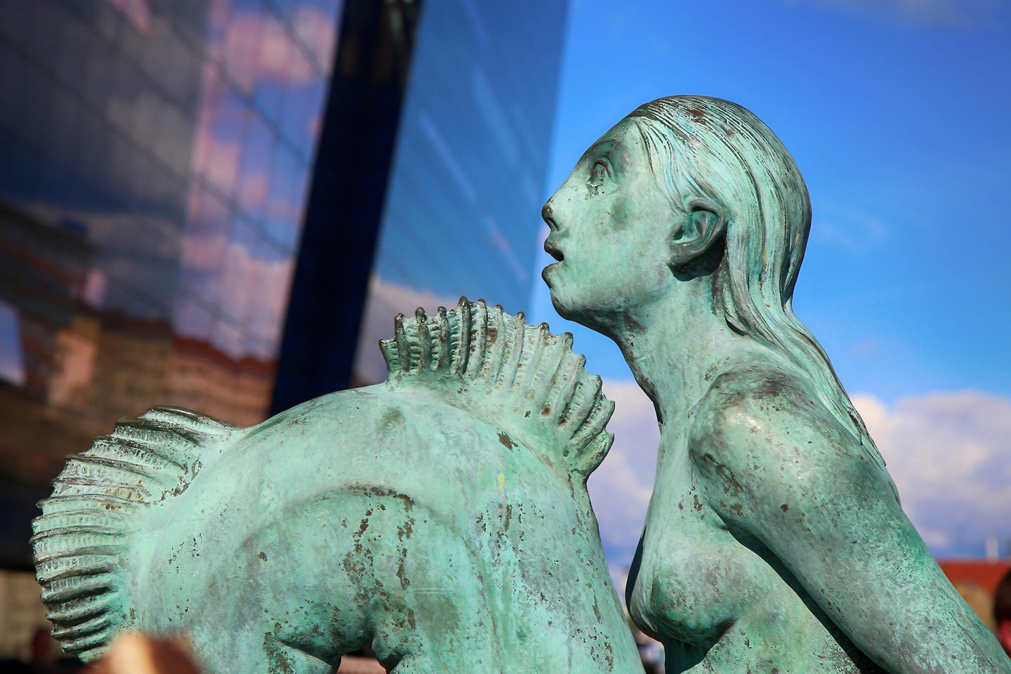 The Little Mermaid statue sits on a shoreline rock overlooking Copenhagen’s calm harbor water. - Copenhagen, Denmark