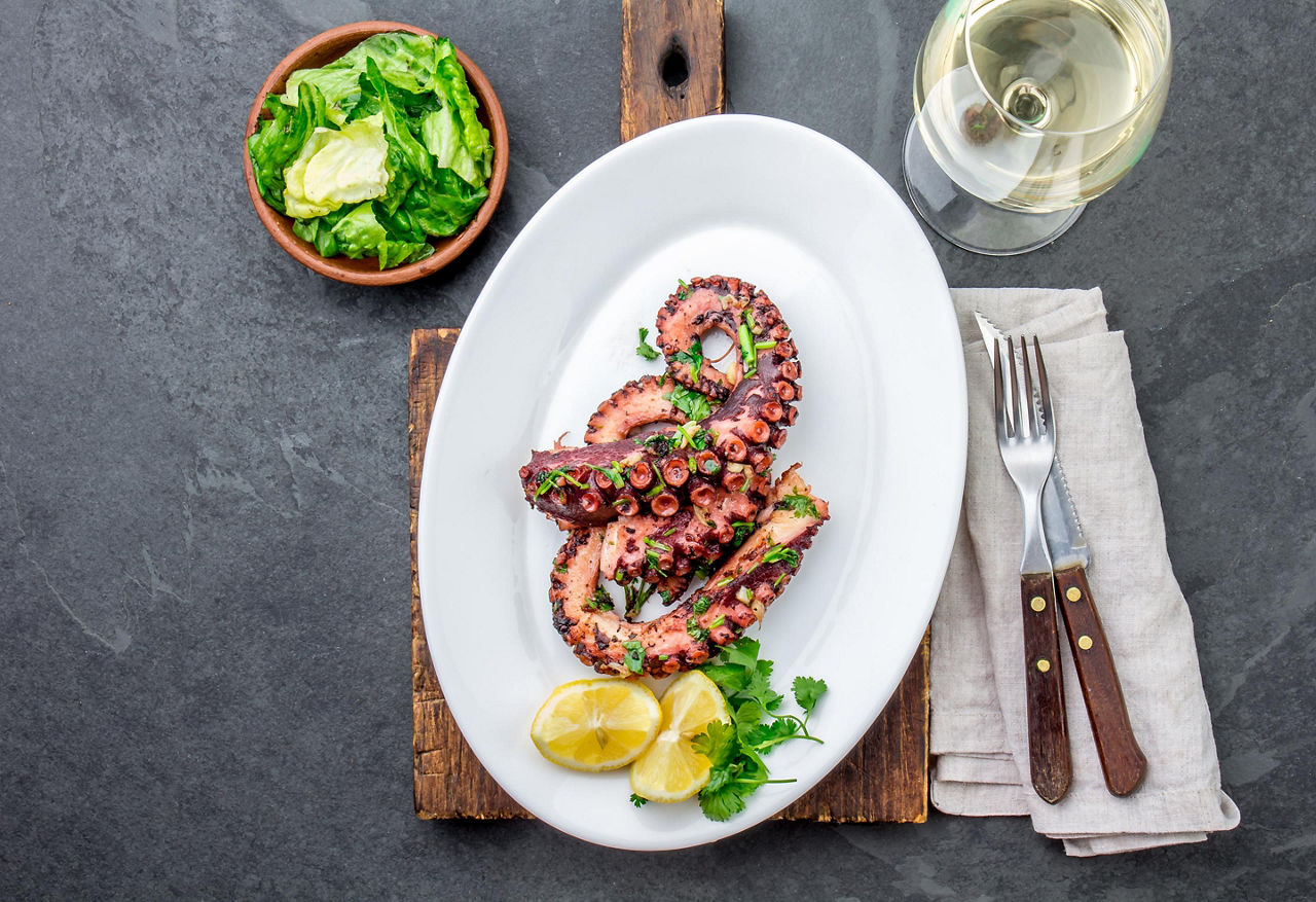 Grilled octopus served with white wine and lemons, on a restaurant in Corfu, Greece