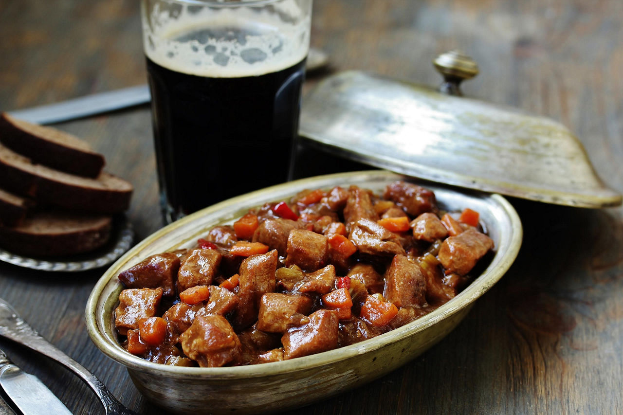 A serving of traditional stew with a pint of beer on the side