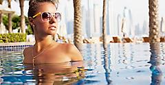 Dubai free happy woman enjoying sunset, relaxing at the luxury poolside. Girl at travel spa resort pool. Summer luxury vacation