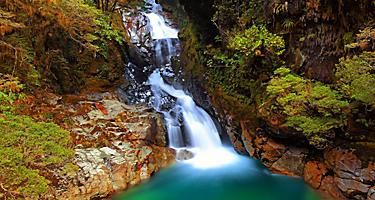 Falls Creek with a waterfall flowing over the mountain in the National Fiordland Park, New Zealand