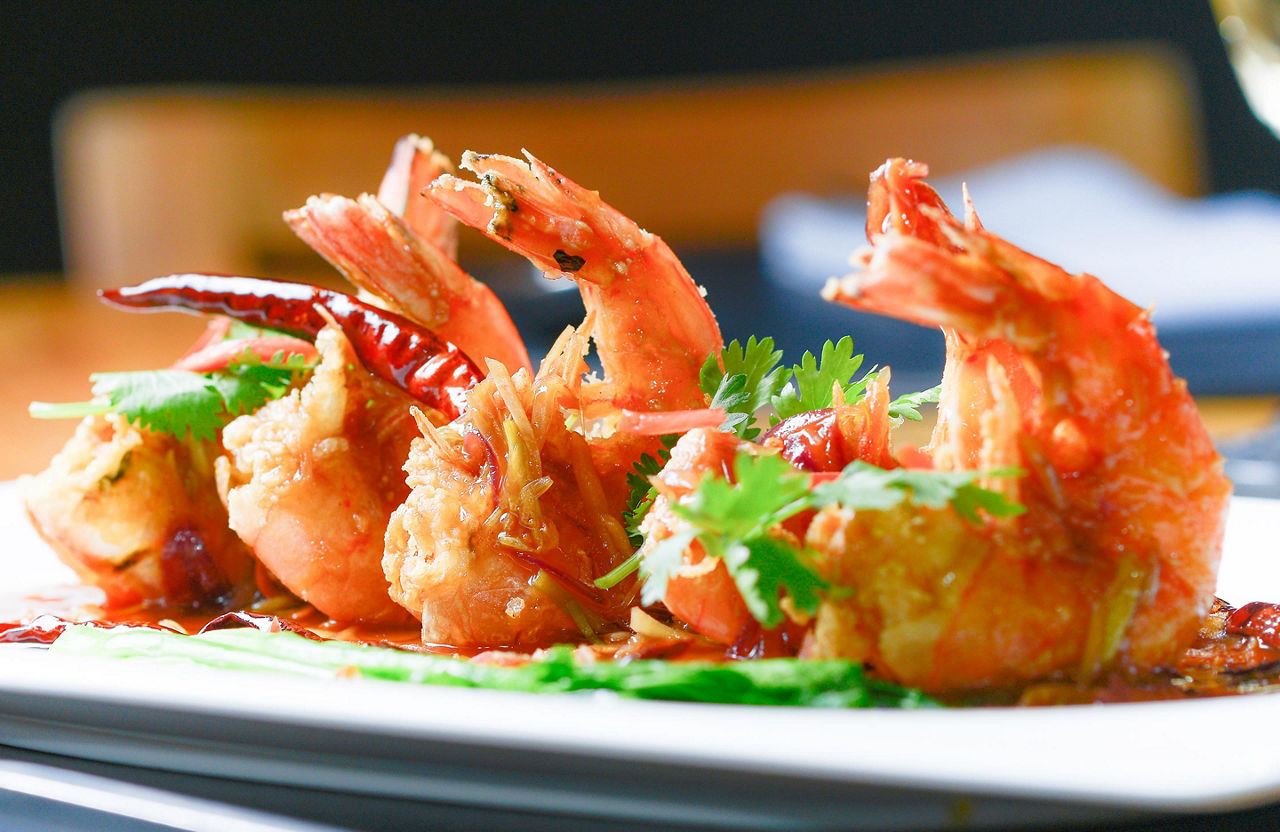Four fried shrimp on a white plate