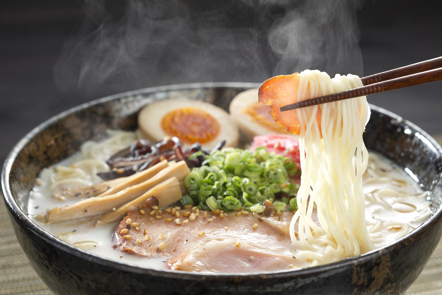 A steaming bowl of Fukuoka ramen features thin noodles, rich broth, and sliced toppings. - Fukuoka, Japan