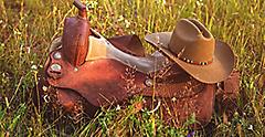 Texas rancher’s cowboy hat and boots laid on green grass. Galveston.