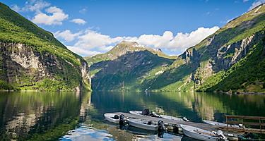 Multiple small boats docked at a pier in Geiranger, Norway,