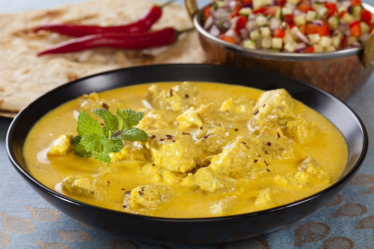 Indian pork curry in a creamy sauce served with naan bread, salad, and rice