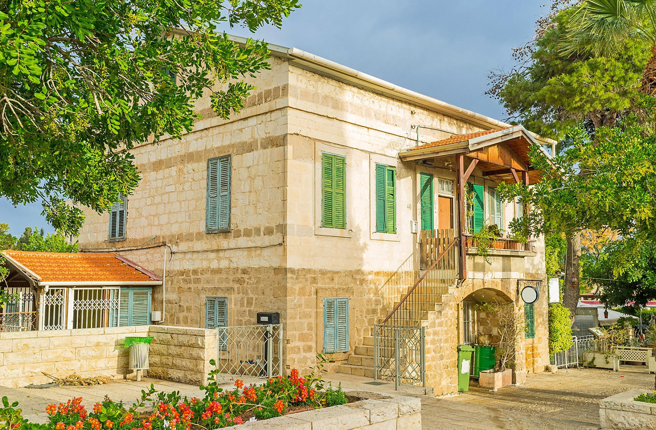 A typical house from the German colony surrounded by trees and flower beds in Haifa, Israel