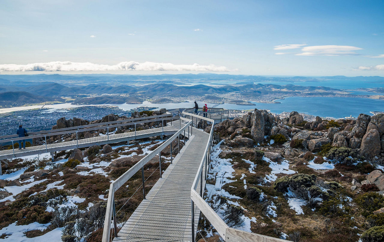 A boardwalk through an icy grassy landscape with views of Hobart, Tasmania