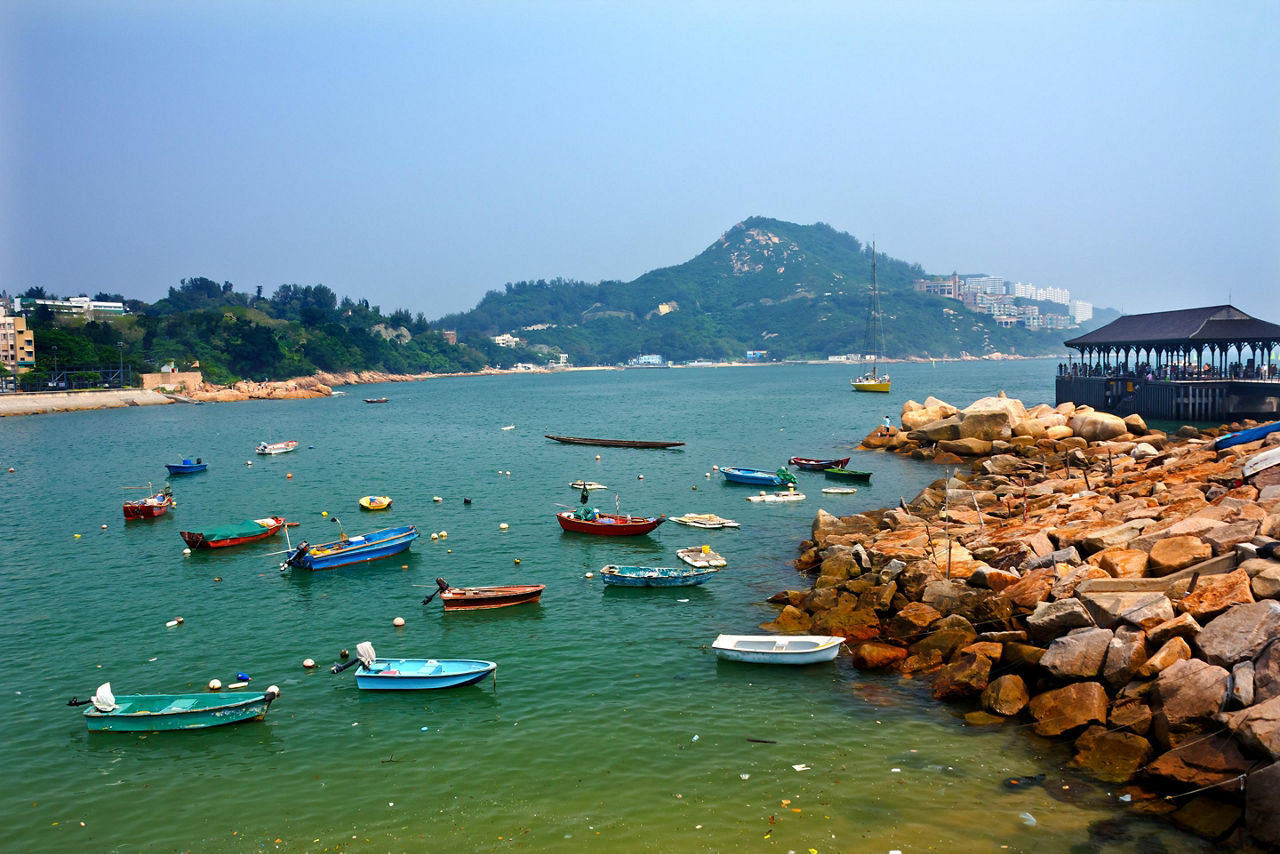 Boats out on the harbor alongside a rocky coast in Hong Kong