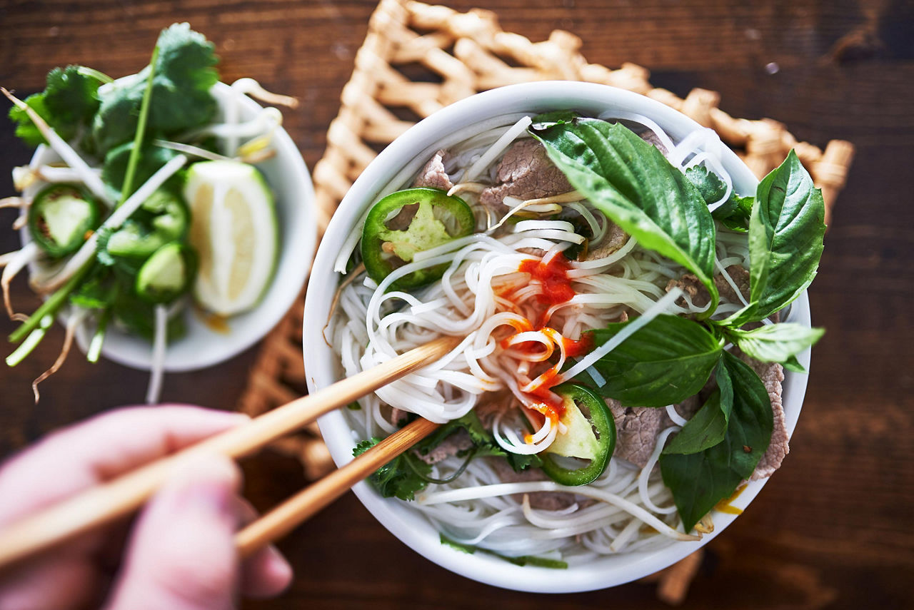 Vietnamese Pho with spicy Sriracha and chopsticks