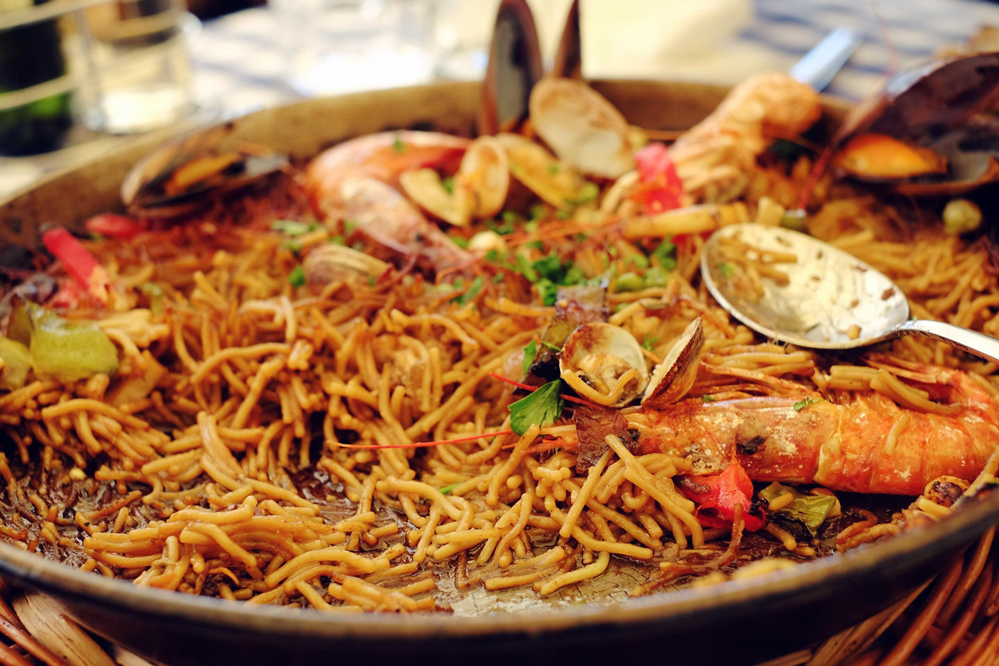 Noodle paella sits in a pan, its golden strands layered with seafood and rich broth. - Ibiza, Spain