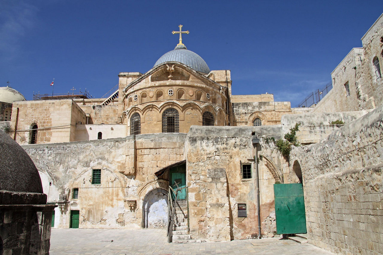 Church of the Holy Sepulchre made out of stones with a blue dome and cross over it with blue skies in Jerusalem, Israel