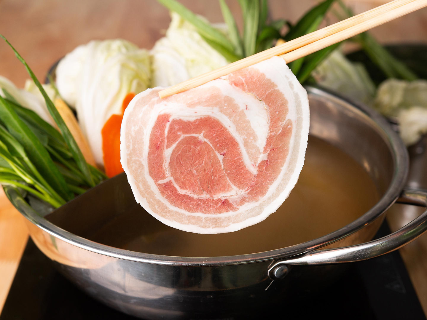 A hearty Kagoshima meat soup simmers with black pork, vegetables, and rich, savory broth. - Kagoshima, Japan