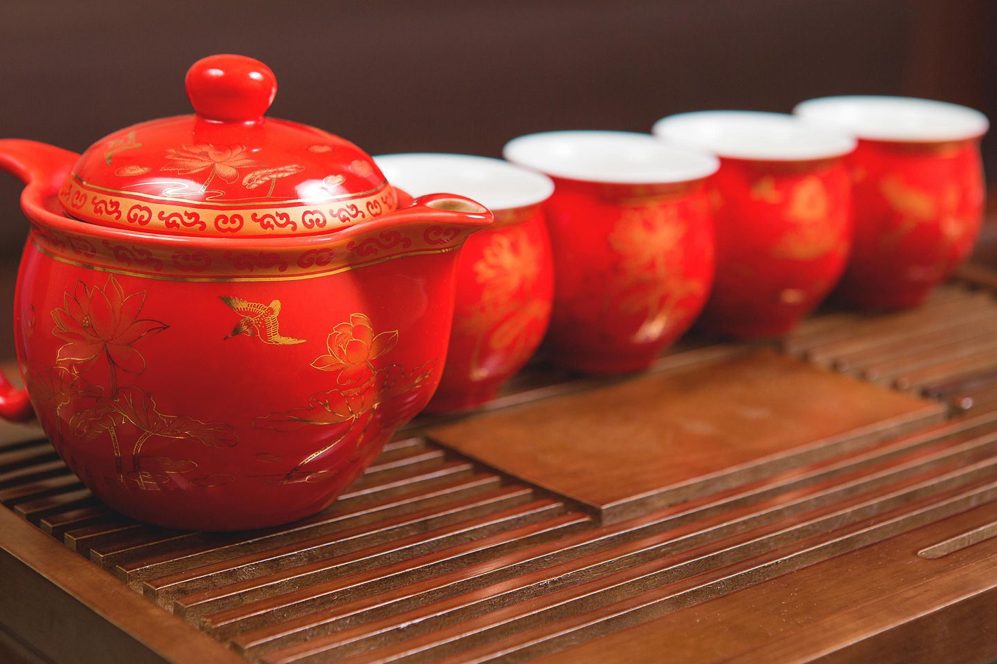 A red tea set with asian designs on a wooden platform in Taiwan.