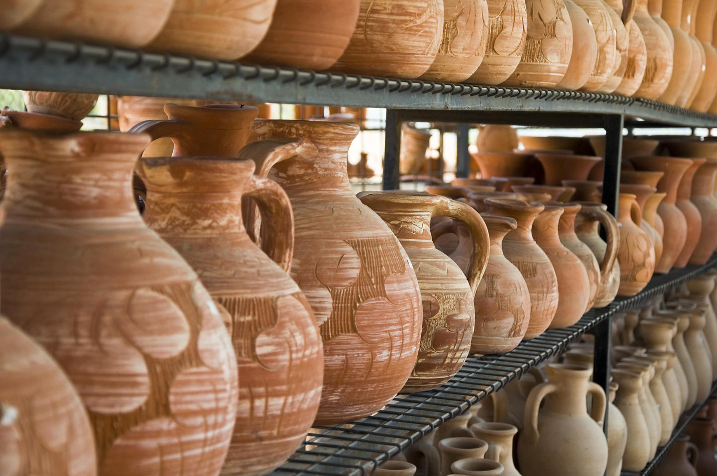 Clay pots sit neatly outside a shop, showcasing simple, earthy Greek craftsmanship. - Olympia, Greece