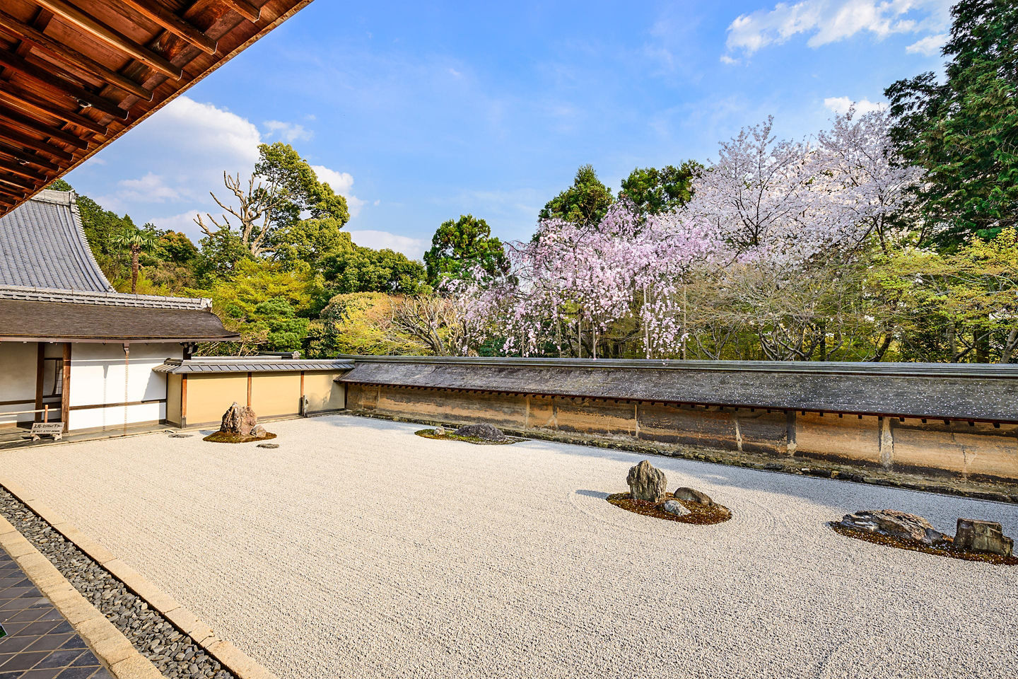 Raked white gravel surrounds simple stone arrangements, creating a calm, balanced Zen garden scene in Ryoan Temple. - Kyoto, Japan