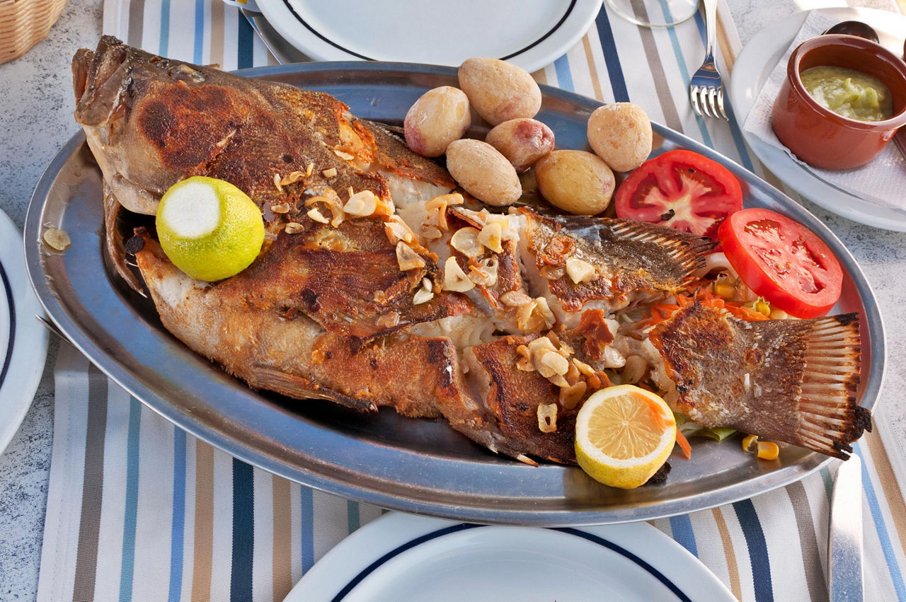A whole roasted fish on a silver plate