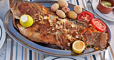 A whole roasted fish on a silver plate