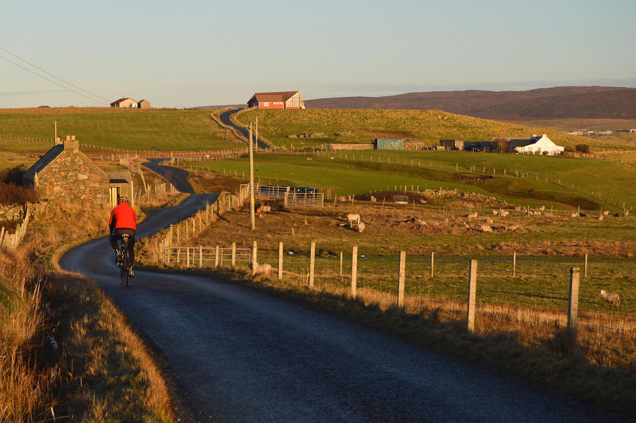 A man bicycling on a road in Lerwick/Shetland, Scotland