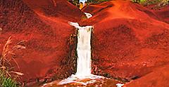 The famous Red Dirt Falls, a cascading waterfall of fresh water over the iron-rich basalt rock in Waimea Canyon State Park, located on the west side of the island of Kauai, Hawaii, United States