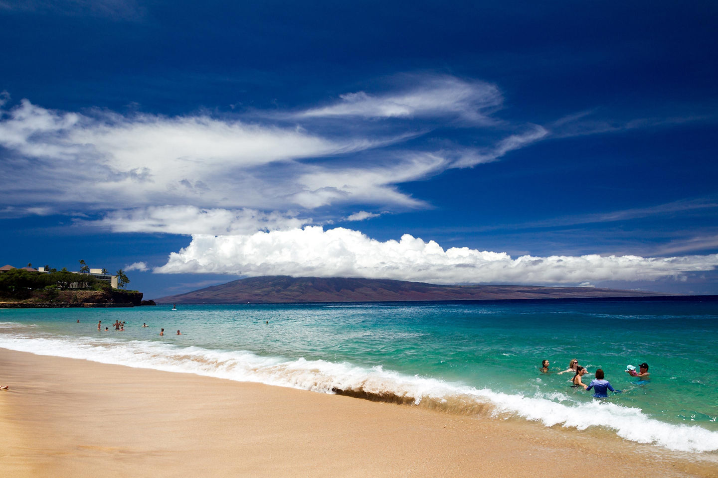 Kāʻanapali Beach curves along golden sand with clear blue water and palm‑lined Maui resorts. - Maui, Hawaii