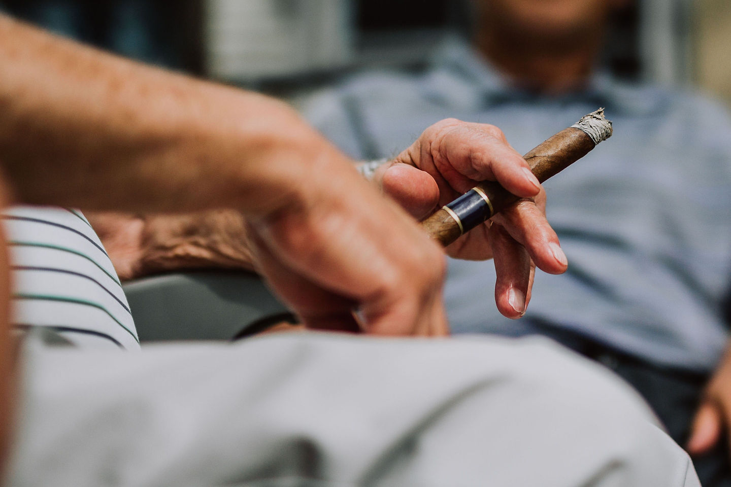 Two men relax in Miami, enjoying Cuban cigars. - Miami, Florida