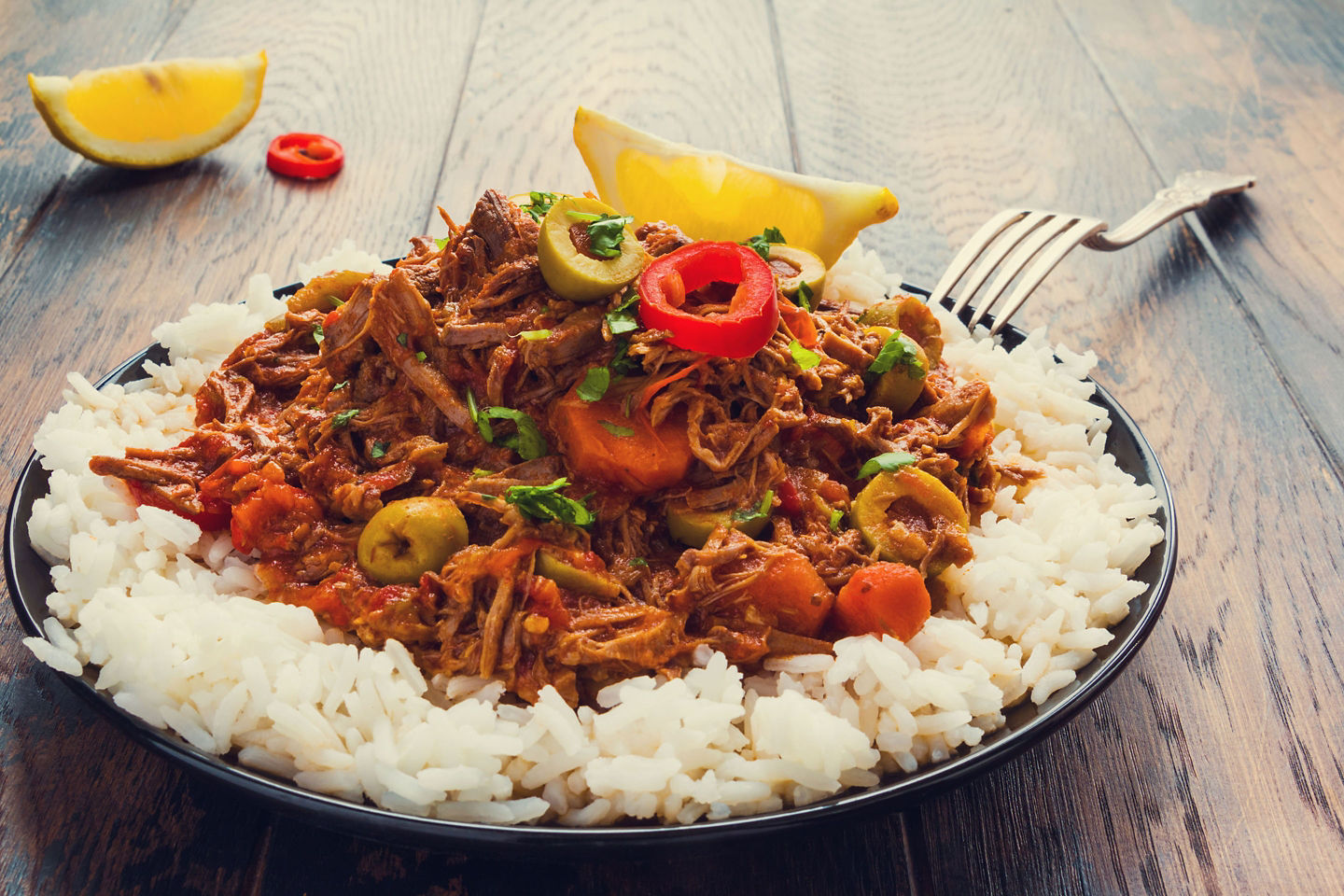 A plate of ropa vieja features tender shredded beef with peppers, served alongside classic Cuban sides. - Miami, Florida