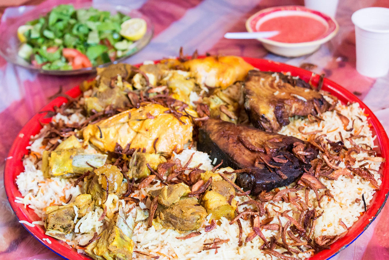 A traditional arabic meal with rice, meats, and sauces