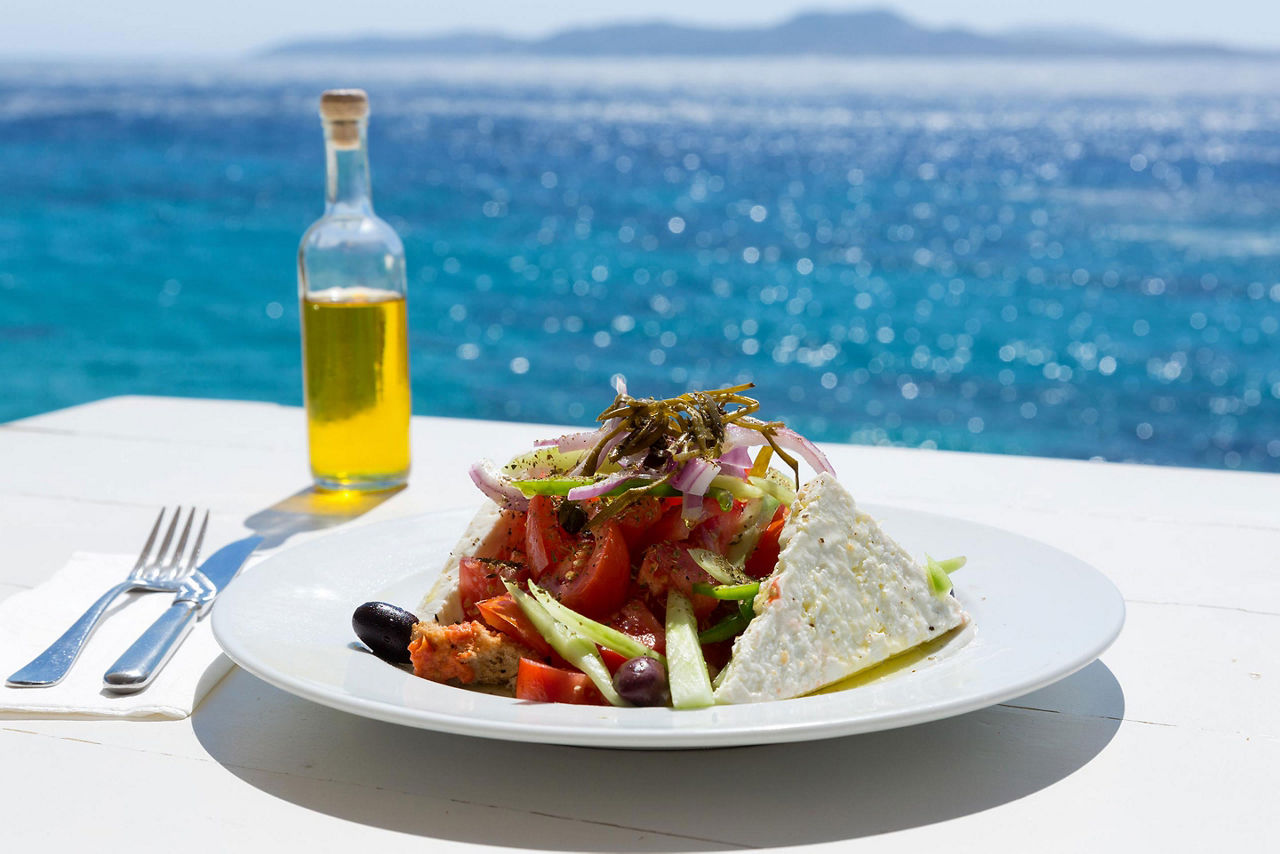 Greek salad and olive oil on sunny seaside restaurant in Mykonos, Greece