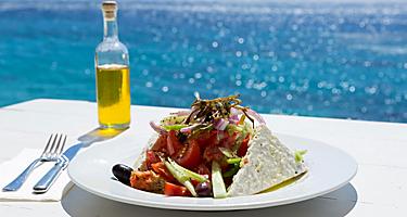 Greek salad and olive oil on sunny seaside restaurant in Mykonos, Greece