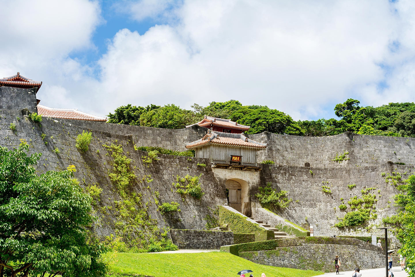 Shuri Castle’s Kyūemon Gate displays bright red wooden architecture against Okinawa’s clear blue sky. - Okinawa, Japan 