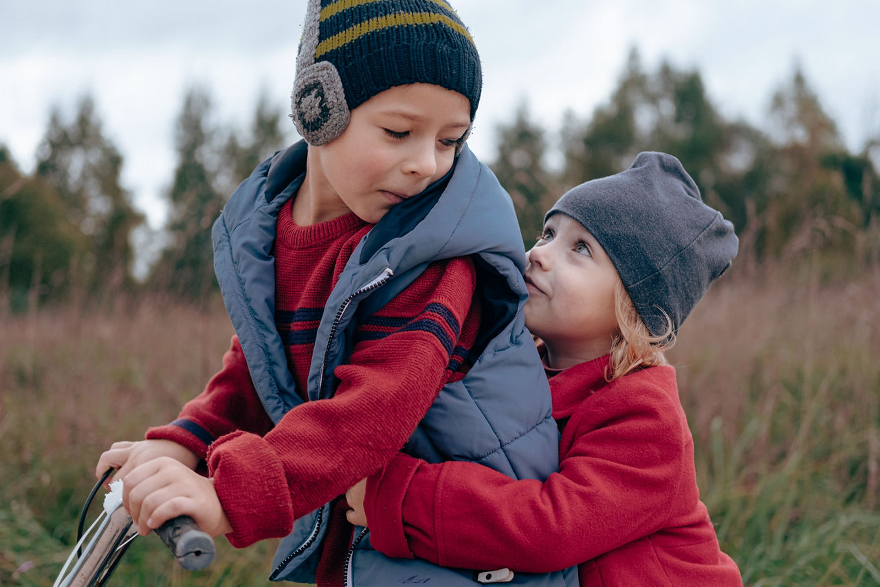 Brother and sister sitting at bicycle together. 