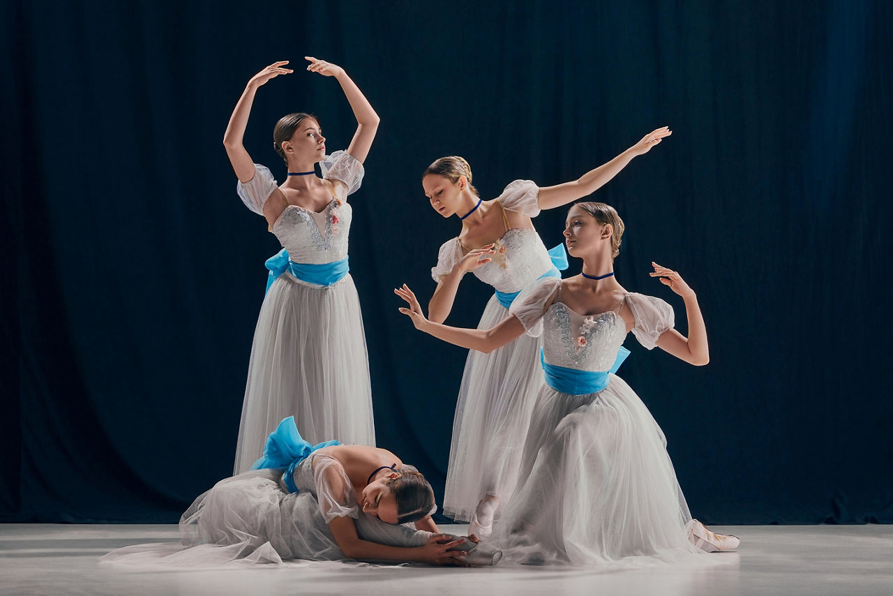 Four ballerinas against dark backdrop on stage. Orlando Ballet.