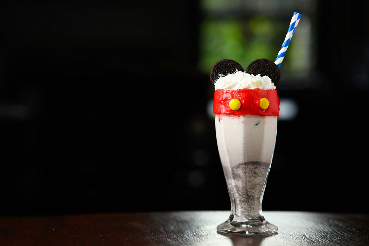 A Mickey Mouse themed milkshake with a straw in it. 
