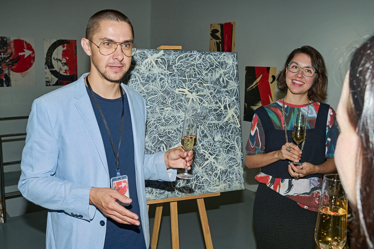 Young male worker of art gallery museum with glass of champagne 