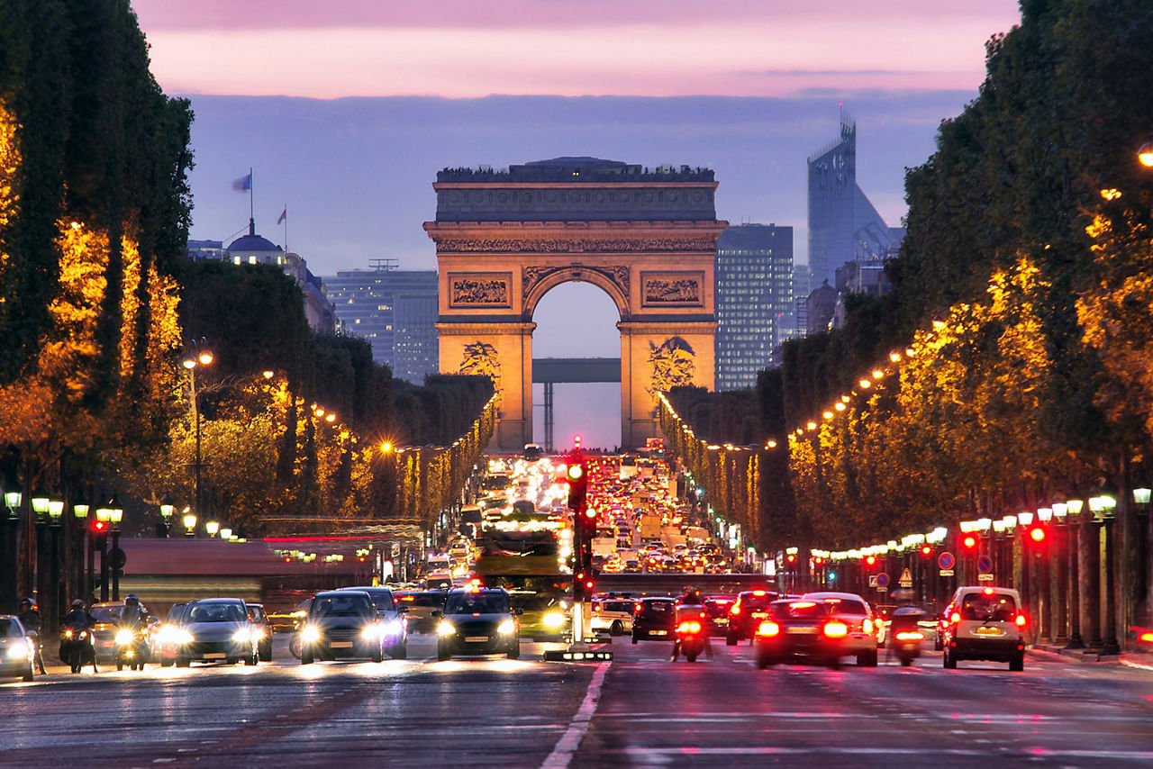 view of Arc de Tripmphe at night with cars driving in Paris. Europe.