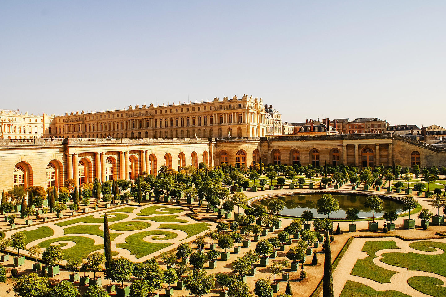 Versailles’ palace stretches behind manicured gardens, its grand façade reflecting France’s royal legacy. - Paris, France