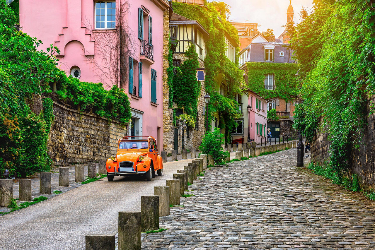 orange car driving along an old street in Paris. Europe.